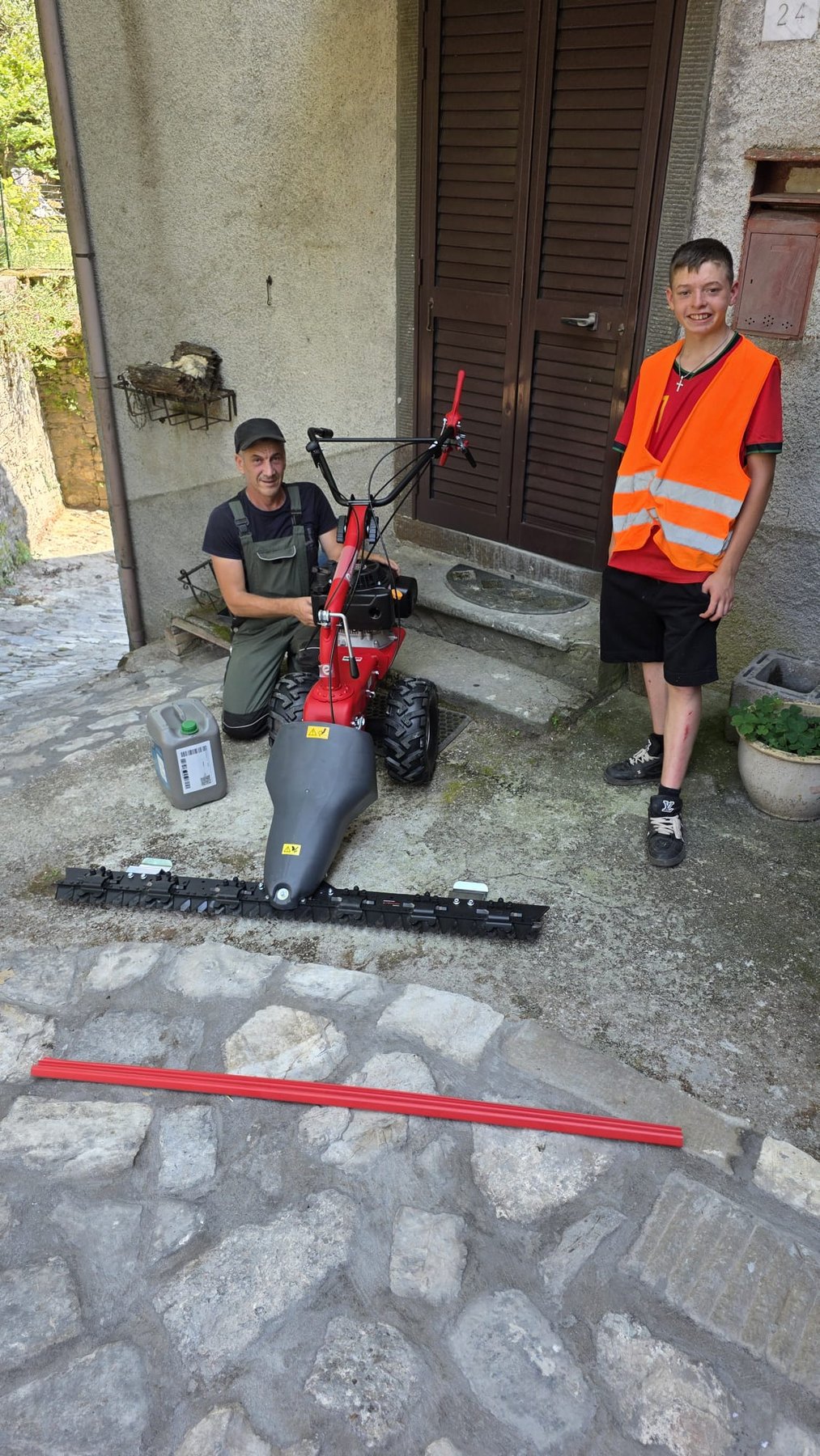 Jamie beside a newly acquired grass-cutting machine with another worker